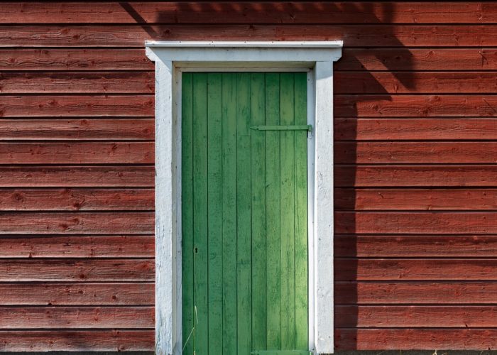 une porte de chalet peinte en vert qu'il faut entretenir rapidement